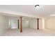 Spacious basement with carpeted floors, wooden support columns, and a doorway leading to another room at 6333 Silver Moon Ct, Indianapolis, IN 46259