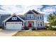 Charming two-story home with a combination of navy and gray siding and a red front door at 6481 W Treeline Ln, McCordsville, IN 46055