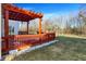 Cozy wooden back deck with a bright orange pergola overlooks the yard and neighboring trees at 7939 Crackling Ln, Indianapolis, IN 46259