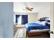 A bedroom featuring a ceiling fan, large window, and a neatly made bed with blue bedding at 7939 Crackling Ln, Indianapolis, IN 46259