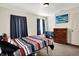Bright bedroom featuring neutral walls, red and gray bedding, and simple furnishings at 7939 Crackling Ln, Indianapolis, IN 46259
