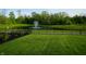 Community pond and fountain view from manicured lawn and black metal fence at 804 Whispering Oaks Dr, Carmel, IN 46032