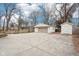 Detached garage with large driveway featuring basketball hoop, wooden fence, and a shed at 8190 Jordan Ln, Indianapolis, IN 46240