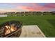 Backyard with a fire pit and view of houses across the pond at sunset at 9034 Faulkner Dr, Indianapolis, IN 46239