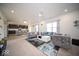 Open-concept living room featuring stylish gray sofas, a modern ceiling fan, and seamlessly connected kitchen area at 10202 Meadow Path Ln, Indianapolis, IN 46239