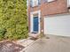Welcoming front entrance with a vibrant blue door, lush greenery, and a convenient attached garage at 11936 Esty Way, Carmel, IN 46033