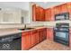 Well-lit kitchen with wooden cabinetry, black appliances, and double basin sink at 11936 Esty Way, Carmel, IN 46033