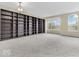 Sunlit living room with floor-to-ceiling bookcase, gray carpet, and large windows at 11936 Esty Way, Carmel, IN 46033