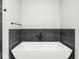 Close-up of modern bathroom soaking tub with matte black fixtures against dark tiled backsplash at 319 E 16Th St # 302, Indianapolis, IN 46202