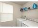 A well-lit laundry room with a window and modern washer and dryer units with storage shelf at 3219 E Maygrove Dr, Danville, IN 46122