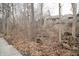 View of the backyard through the bare trees, showing the side of the building from behind the lot line at 4264 Foxglove Trce, Indianapolis, IN 46237