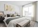Bright bedroom featuring a bed with a light headboard, bench, neutral bedding, and a large window for natural light at 447 Leota St, Indianapolis, IN 46203