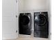 A laundry room featuring a modern, front-loading washer and dryer set in sleek black at 517 Steinbeck Pl, Carmel, IN 46032