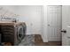 Functional laundry room with modern washer and dryer units, overhead shelving, and stylish rug at 5784 Cherrywood Ln, McCordsville, IN 46055