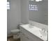 Bathroom with double sink vanity, glass block window, and toilet at 7144 Sandalwood Dr, Indianapolis, IN 46217