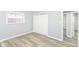 Light-filled bedroom featuring gray walls, vinyl flooring, a double door closet, and a bright window at 8230 E 12Th St, Indianapolis, IN 46219