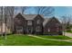 Elegant brick home with manicured lawn, complemented by mature trees and a charming walkway at 895 Baywood Ct, Columbus, IN 47201