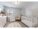 Bedroom featuring a crib, rocking chair, mural, toy chest, and dresser at 10441 Alexia Dr, Indianapolis, IN 46236
