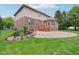 Beautiful backyard featuring a stone patio, lush lawn, well-maintained landscaping, and brick exterior of the home at 13133 Brooks Landing Pl, Carmel, IN 46033