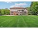 Lush green backyard showcasing a spacious lawn, outdoor living space, and the rear of the home with brick and siding at 13133 Brooks Landing Pl, Carmel, IN 46033
