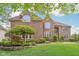 Charming brick home featuring an arched entryway, manicured lawn, and professionally landscaped yard at 13133 Brooks Landing Pl, Carmel, IN 46033