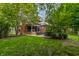 Spacious backyard with a covered outdoor living area, kitchen, mature trees, and lush green grass at 1320 N New Jersey St, Indianapolis, IN 46202