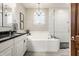 Bathroom featuring a double sink vanity with black countertop, soaking tub, and glass-enclosed shower at 1320 N New Jersey St, Indianapolis, IN 46202