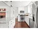 Open concept kitchen featuring white cabinets, granite counters, stainless appliances, and brick fireplace at 1621 Nottingham Dr, Indianapolis, IN 46240