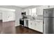 Bright kitchen with stainless steel appliances, granite countertops, white cabinets, and wood flooring at 1842 Tallman Ave, Indianapolis, IN 46218