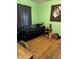 A bedroom featuring a window with dark curtains, hardwood floors, and green walls at 410 N Euclid Ave, Indianapolis, IN 46201