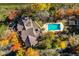 Aerial view of a beautiful home with a backyard pool surrounded by colorful trees during the fall season at 5015 Watersite Cir, Indianapolis, IN 46254