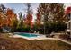Backyard with an in-ground pool and outdoor seating, surrounded by a vibrant display of autumn foliage at 5015 Watersite Cir, Indianapolis, IN 46254