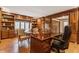Home office features wood-paneled walls, custom built-in bookshelves, and a comfortable sitting area by the window at 5015 Watersite Cir, Indianapolis, IN 46254