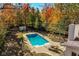Aerial view of a clear blue swimming pool surrounded by lounge chairs, greenery, and changing fall foliage at 5015 Watersite Cir, Indianapolis, IN 46254