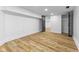 View of the finished basement with wood flooring, white walls, and access to storage at 6470 Jackson St, Indianapolis, IN 46241