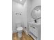 Modern bathroom with black fixtures, round mirror and wood look flooring at 6470 Jackson St, Indianapolis, IN 46241