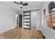 Bright bedroom featuring modern ceiling fan, wood floors, and sliding barn door at 6470 Jackson St, Indianapolis, IN 46241