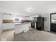 Bright kitchen features white cabinets, island, stainless steel appliances, and wood grain vinyl flooring at 718 Indiana Ave, Shelbyville, IN 46176