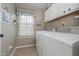 Well-lit laundry room with white washer and dryer, window, and ample storage space at 8238 Armadale Ct, Indianapolis, IN 46236