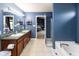 Main bathroom featuring double sinks, a soaking tub, and modern fixtures in a serene blue color scheme at 8430 Templederry Dr, Brownsburg, IN 46112