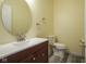 Bathroom with laminate flooring, round mirror over the sink, white toilet and yellow walls at 9769 Green Knoll Dr, Noblesville, IN 46060