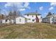View of the backyard, detached garage and white house with brick chimney at 1023 W 7Th St, Anderson, IN 46016