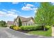 Charming stone home featuring manicured landscaping, a brick arch above the window, and lush green trees at 13902 Rue Royale Ln # 62, McCordsville, IN 46055