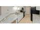 Galley kitchen featuring granite countertops, stainless steel sink, and black appliances, enhanced by ample lighting at 2218 Colfax Ln, Indianapolis, IN 46260
