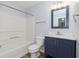 Bright bathroom features a white shower-tub combo, a blue vanity with a white countertop, and a square mirror at 3113 Cassara Dr, Indianapolis, IN 46203