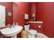 A cozy powder room featuring red walls, pedestal sink, and tiled floors at 4615 Crystal Lake Dr, Indianapolis, IN 46240