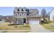Beautiful two-story home featuring dormer windows, a covered front porch, brick accents, a well-kept lawn, and a two-car garage at 5524 Goodwin St, Indianapolis, IN 46234
