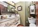 Olive bathroom featuring ornate mirror, white vanity, and decorative accents at 5529 W 29Th Pl, Indianapolis, IN 46224
