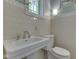 Vintage bathroom with tile walls and pedestal sink at 6009 N Washington Blvd, Indianapolis, IN 46220
