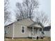Cozy home with neutral siding, a front porch, simple landscaping and leafless winter trees in background at 620 W Madison St, Alexandria, IN 46001